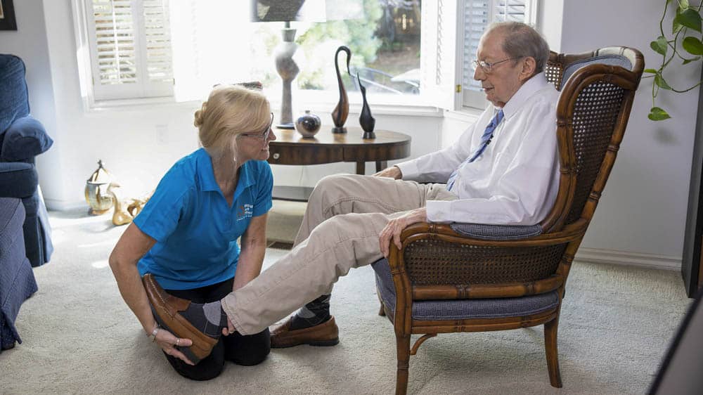 Older adult removing shoes and relaxing feet at home